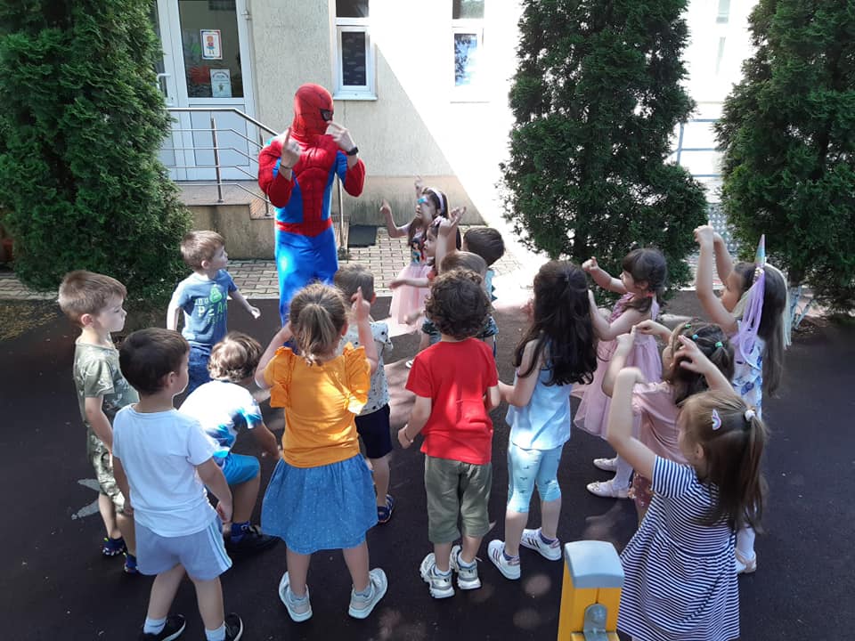 Copii jucându-se cu Spiderman în curtea grădiniței